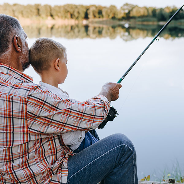 Knee Replacement can impact daily life. Grandfather fishing with grandson on a lake